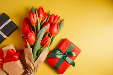 Mothers' day. Red tulips with gift boxes. Easter holiday. Yellow background