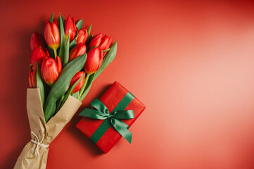 Mothers' day. Red tulips with gift box. Easter holiday. Red background, copy space.