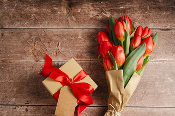 Mothers' day. Red tulips with gift box. Easter holiday. Wooden background, copy space.