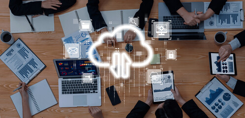 Business team engaging in cloud technology discussions, analyzing data and reports on devices in a modern workspace, showcasing collaboration and digital innovation. Trope