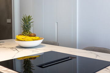 Close-up of modern kitchen island with marble surface and bowl of fresh tropical fruits