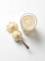 Creamy Protein Shake with Measuring Scoop of Nutritional Powder on White Background