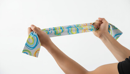 Hands Stretching Colorful Wavy Patterned Resistance Band or Fabric Against White Background for Fitness and Activewear Textile Design.