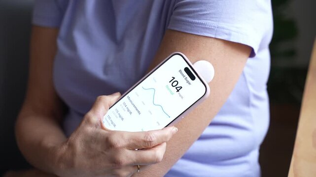 Woman checking blood sugar using smartphone and sensor