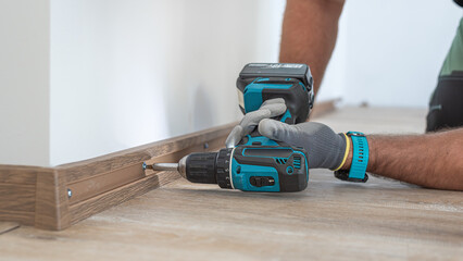 Installing elegant plastic baseboard, showcasing skilled craftsmanship in home improvement and renovation. Worker using a screwdriver to mount skirting board, plinth.