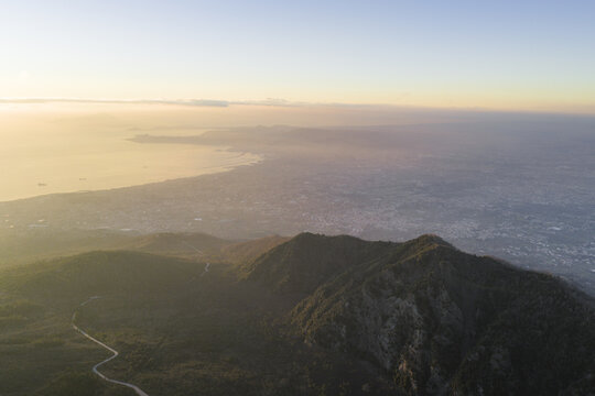 Aerial view of the rugged mountain peaks meet the distant, hazy coastline, a symphony of earth tones fading into the soft blue horizon, Ercolano, Campania, Italy.