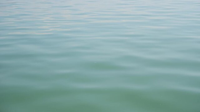 Close up on clam and serene sea or lake water texture slowly moving. Sea of Galilee in Israel Holy Land where Jesus made miracles. Lake Kinneret peaceful water. Blue turquoise colors