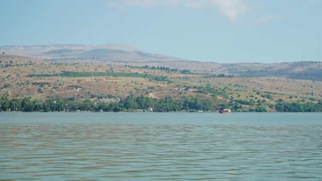 Sea of Galilee and view on capernaum with religious tour boat sailing in lake. Sunny summer day in northern Israel where Jesus Christ biblical and historical sites are found. Group of pilgrims visit