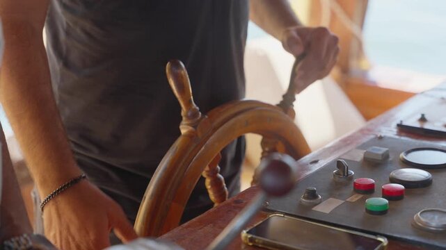 A close-up of person's hands on traditional wooden ship's wheel steering vessel. Control panel with various buttons, dials, and gauges. Small tour boat or wooden ferry. Bright sunny day outdoors