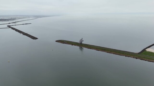 Engineer Surveys Shoreline From Above, Calm Waters Contrast With Tense Mood Of Protective Structure Scene