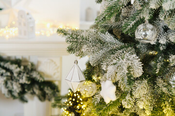 Close up of frosted pine branches with white geometric and star ornaments, warm lights