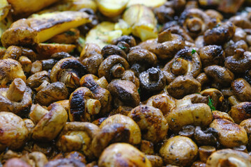 Close up view of hot prepared golden brown button mushrooms and seasoned baked potato pieces