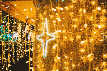 Luminous golden tinsel and hanging string lights with a radiant white star illuminating night celebration.