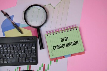 A desk setup featuring a green notebook labeled debt consolidation, a magnifier, charts, and a keyboard, illustrating financial analysis, budgeting, and planning for debt reduction and financial goals