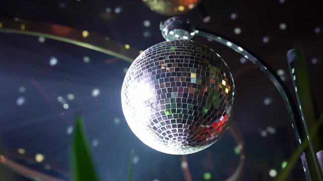 Rotating disco ball reflecting colorful lights across a dark space, creating a vibrant party atmosphere. Shimmering reflections, nightlife energy, dance floor mood, celebration, music and club