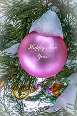 A pink ball on a spruce branch outdoors.