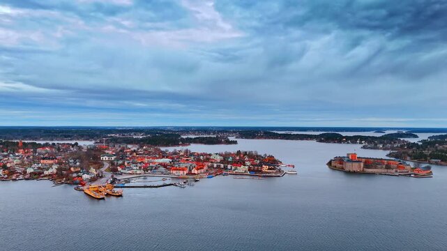 Flying over Lake Malar reflecting overcast grey sky. Aerial perspective on the bright cityscape of Vaxholm, the capital of Stockholm archipelago.