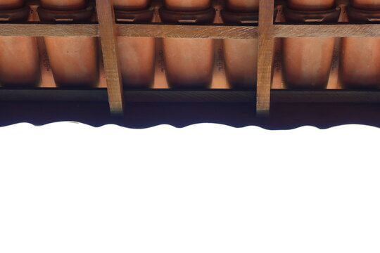 Detailed perspective of overlapping clay roof tiles supported by rustic wooden beams, showcasing traditional construction elements