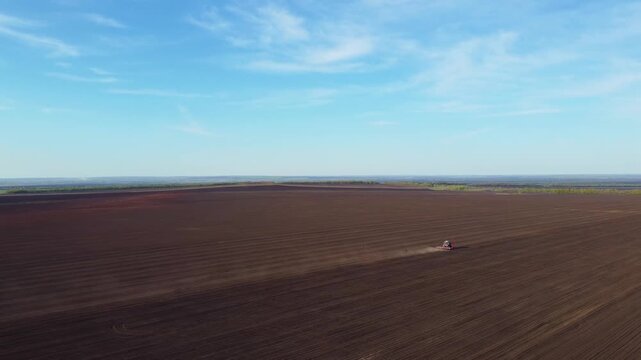 A tractor plowing a field in spring, aerial view
