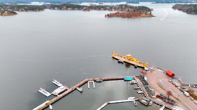 Approaching the berth with a public car ferry that runs between Vaxholm and the nearby island of Rind&ouml;. Small islets at Lake Malar at backdrop. Sweden.