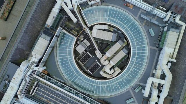 Top down aerial view of industrial rooftop cooling and HVAC systems, glass atrium ceiling, major air vents and ducting