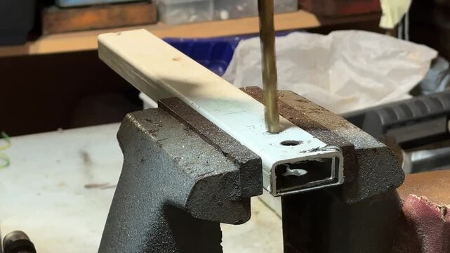 Processing steel element in mechanical workspace showing stable fixation and tool penetration into material for fabrication task, taken handheld. High quality 4k footage