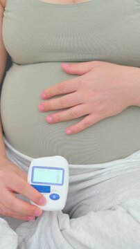 Pregnant woman in her eighth month measuring blood sugar with a portable glucometer. A calm, realistic everyday scene highlighting maternal health, prenatal care, and gestational diabetes management