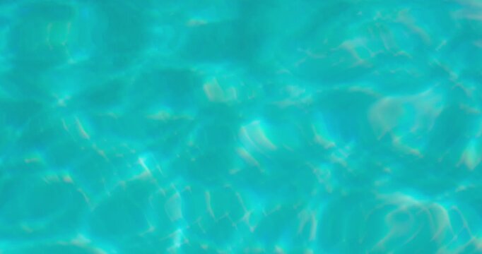 PORTOCOLOM, MALLORCA, SPAIN - OCTOBER, 2025: Sunlight shines on a clear, turquoise pool, gentle ripples move across the water's surface, creating a calming summer background.