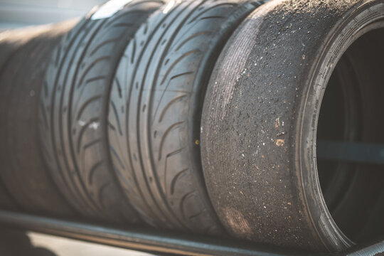 Close-up of used racing tires stacked on a metal shelf