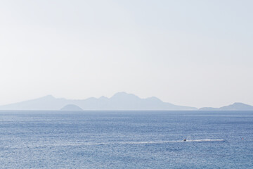 Characteristic features of a Greek island include dry terrain, strong sunlight, blue sea, rocky...