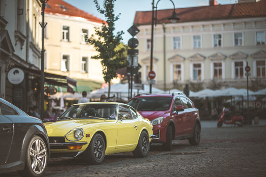 Vintage yellow sports car parked on a cobblestone street in Europe