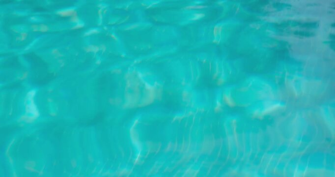 PORTOCOLOM, MALLORCA, SPAIN - OCTOBER, 2025: Clear blue pool water reflects sunlight, causing ripples and refractions on a bright day, a relaxing background.