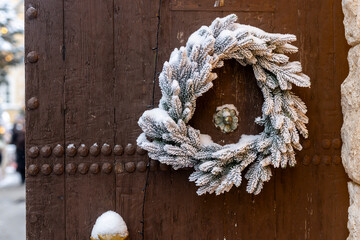 Close up of snowy Christmas wreath made of frosted pine branches hanging on old wooden door, Moscow, Russia.