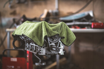 Engine block with exposed gears covered by a green cloth in a workshop setting