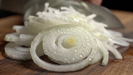Closeup shot of freshly sliced white onions glistening with water droplets on a rustic wooden cutting board ready for cooking or salad preparation highlighting their crisp texture and culinary appeal.