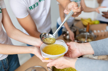 Young volunteers serve hot soup to those in need at a community charity donation center, working together to alleviate hunger and support the homeless. Efforts focused on compassion and care.