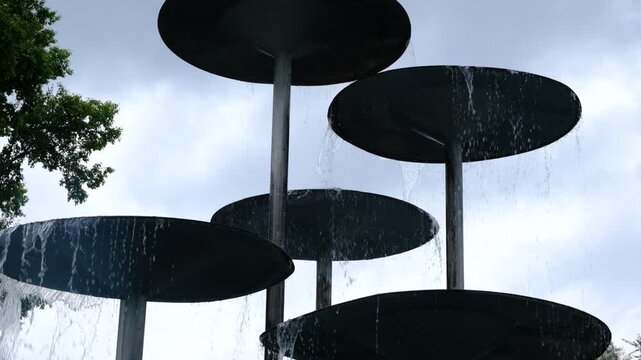 Waterfall fountain flows in streams. Waters running down. Water in the fountain shimmers and shines. Fountains in metal style, durable designs, stainless steel, corten or other metals