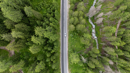 Vue a&eacute;rienne verticale d'une voiture circulant sur une route foresti&egrave;re isol&eacute;e, road trip