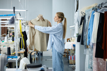 Craftswoman meticulously adjusts garment on mannequin within boutique sewing