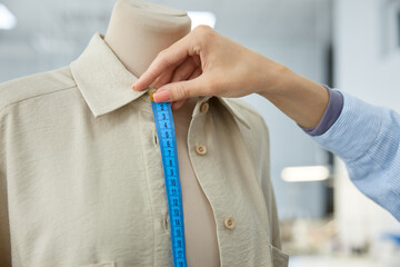 Woman clothing stylist measuring garment for precision in workshop