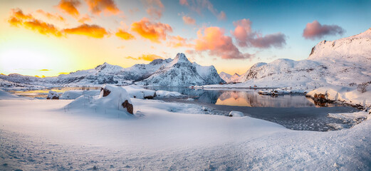 Amazing Flakstadpollen and Boosen fjords with cracks on ice during sunrise with Hustinden mountain on background.