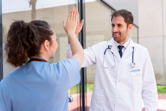 Medical professionals celebrating teamwork and success with a high five, expressing collaboration and partnership in modern healthcare environment, achieving goals together