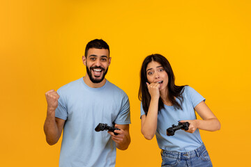A playful Arab man celebrates his online gaming success while a woman nearby shows her...