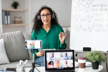 Online Education. Female professor in eyeglasses and headphones teaching remotely working from...