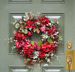 Colorful decorative wreath with fruit and flowers on front door