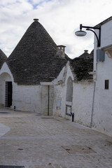 authentic trulli house close-up in alberobello featuring traditional limestone walls, a conical stone roof, and a vintage street lamp against a bright sky