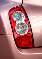 close up of a pink car taillight with reflective lens and glossy paint surface