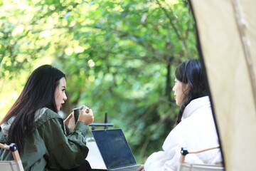 Female Enjoy Moment Talking in front of Their Tent While Working Remote Using Laptop.