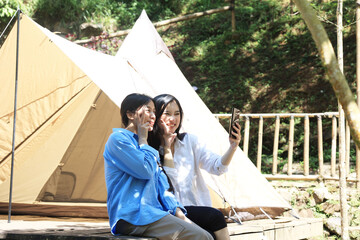 Two Asian Women Take a Selfie Outside a Tent