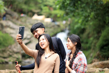 Three Asian Young People Taking Group Selfie Photo While Hiking
